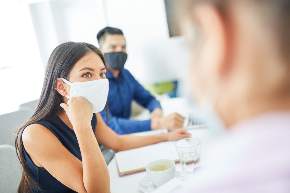 Business woman with face mask because of Covid-19 and corona virus in a meeting or a meeting