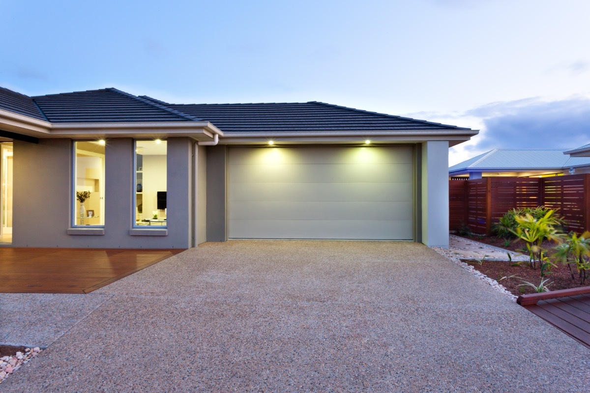 Part of this luxury house includes a garage with a white door and illuminated by two small lights under the ceiling.