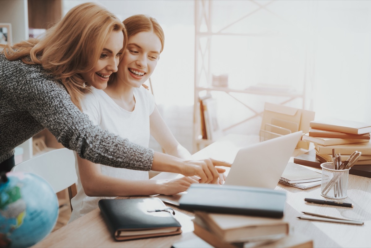 white mother and daughter looking at laptop computer