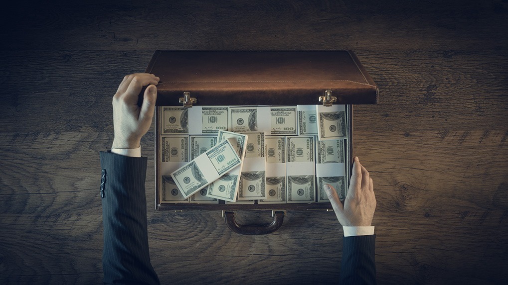 white man's hands opening briefcase full of cash