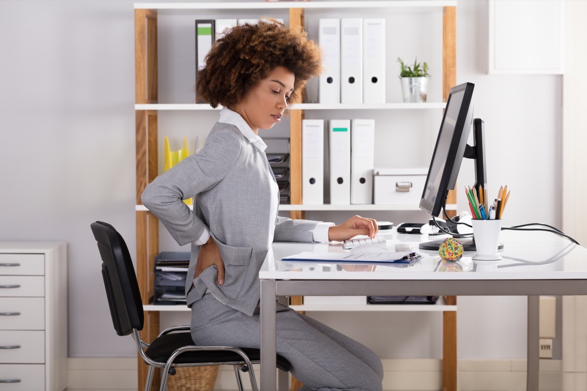 Young Businesswoman Suffering From Back Pain While Working In Office