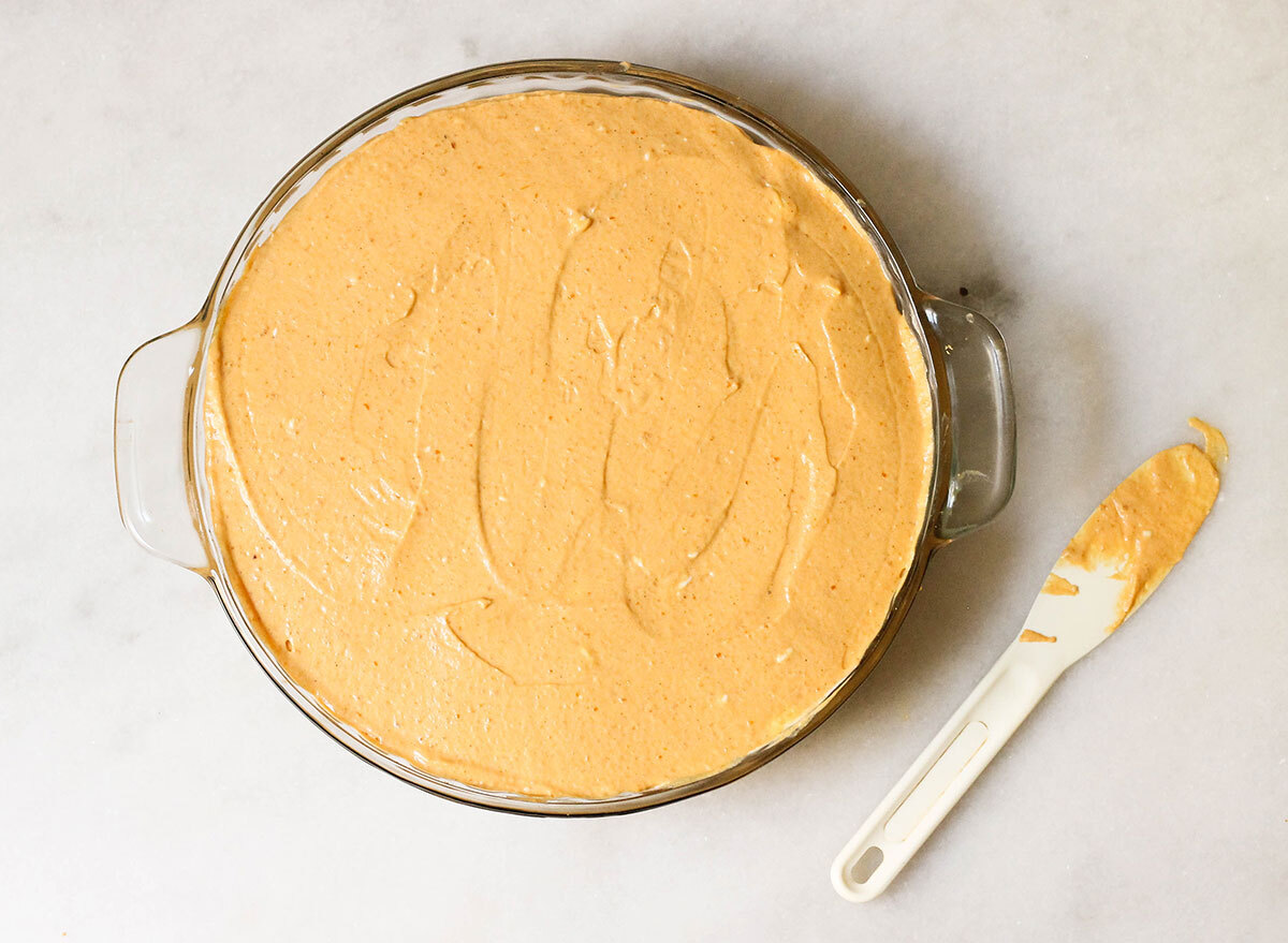 Smoothing out the top of a pumpkin cheesecake before it goes into the oven