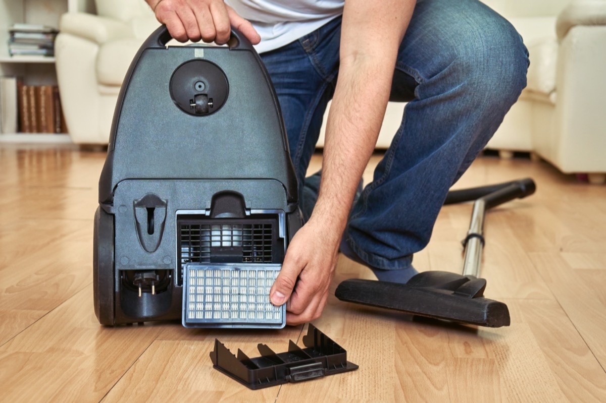 Man replacing an air filter of a vacuum cleaner at home