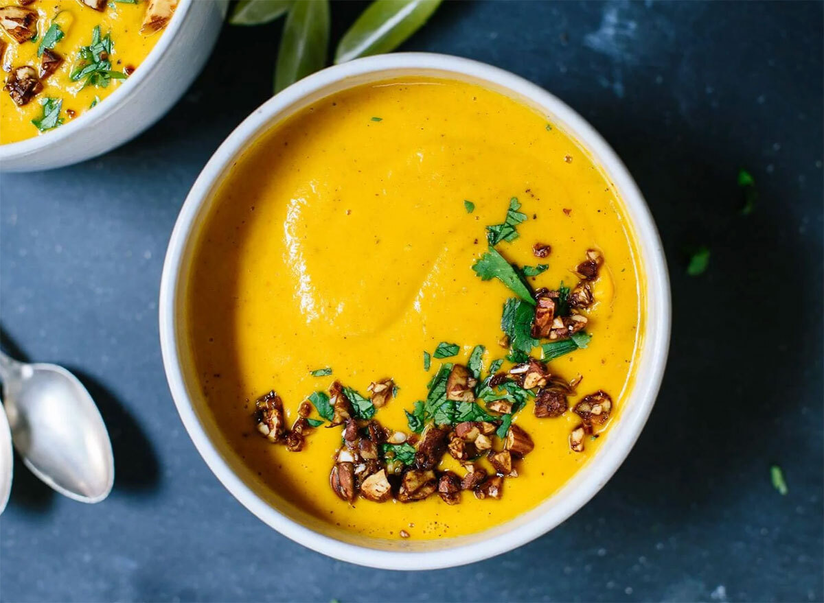 thai carrot sweet potato soup in white bowl with spoon