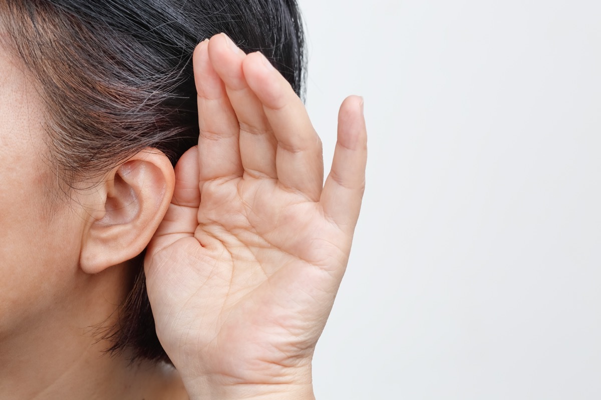 woman with gray hair cupping her ear because she is hard of hearing