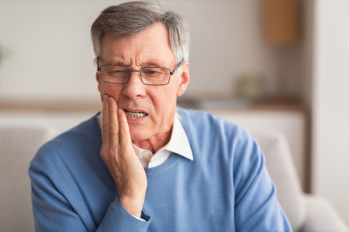 Older man holding his jaw in pain