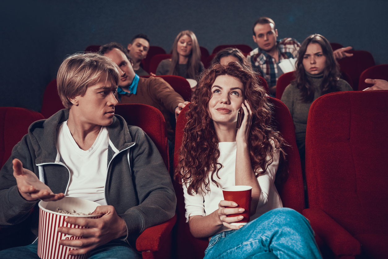 Young red head girl speaks on phone during movie 