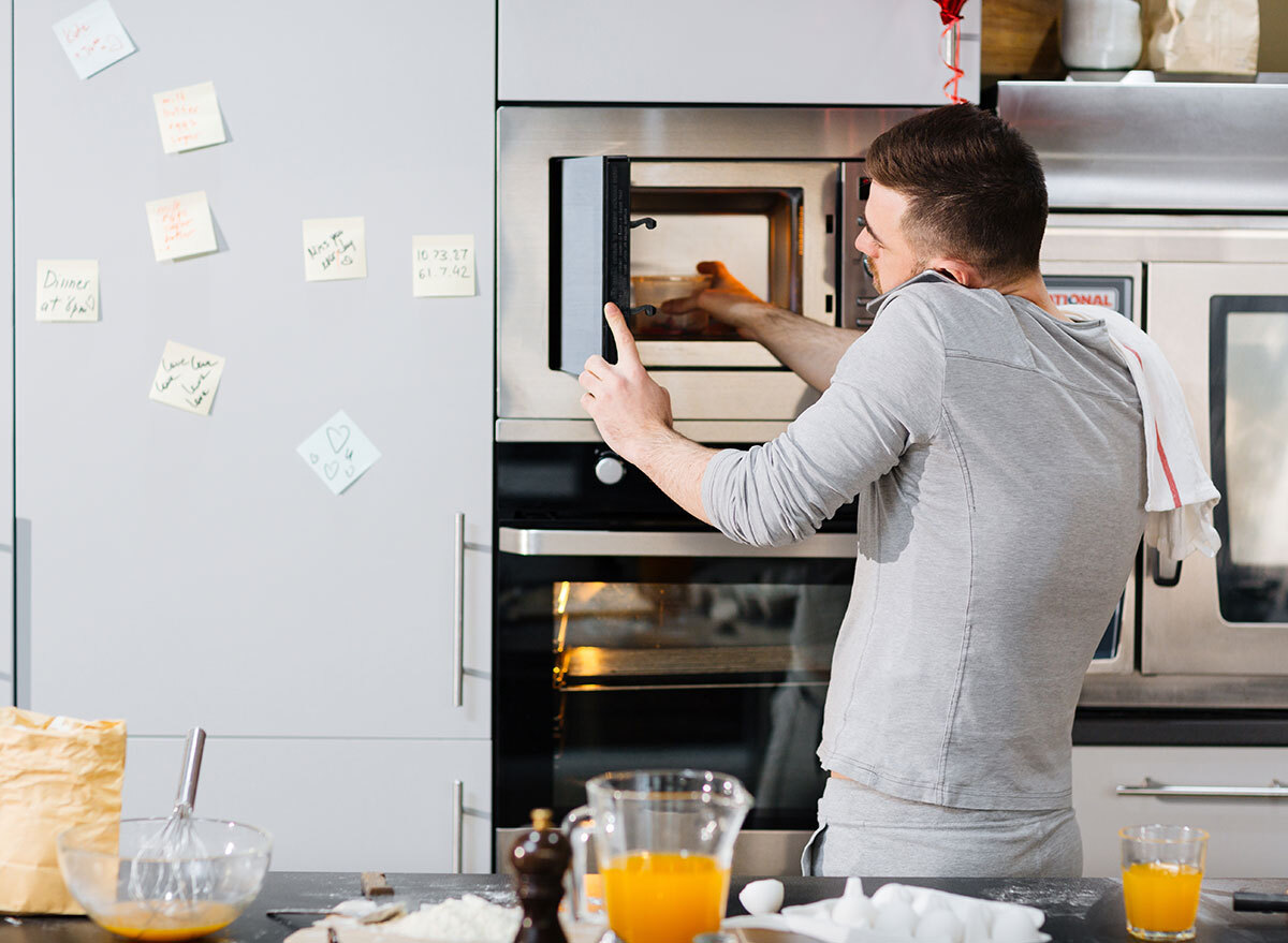 man on phone distracted cooking with microwave