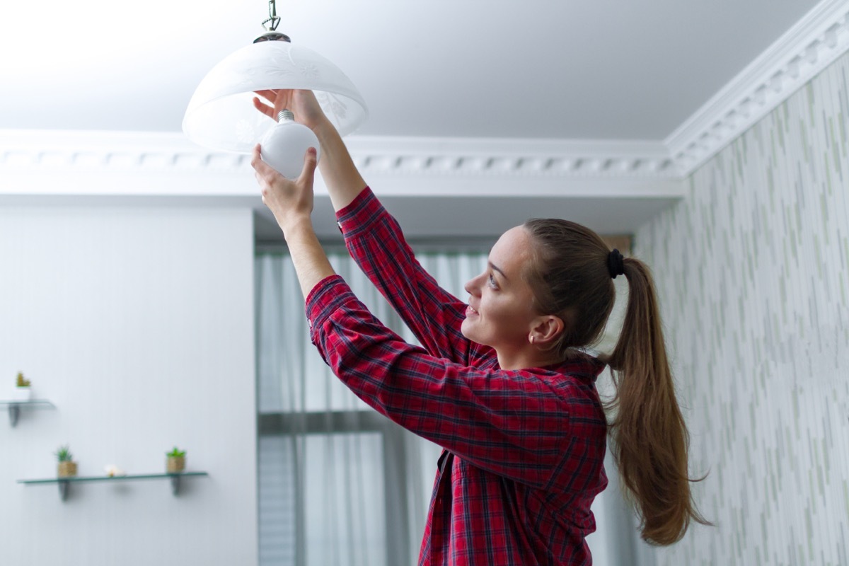 Woman adjust light fixture in house