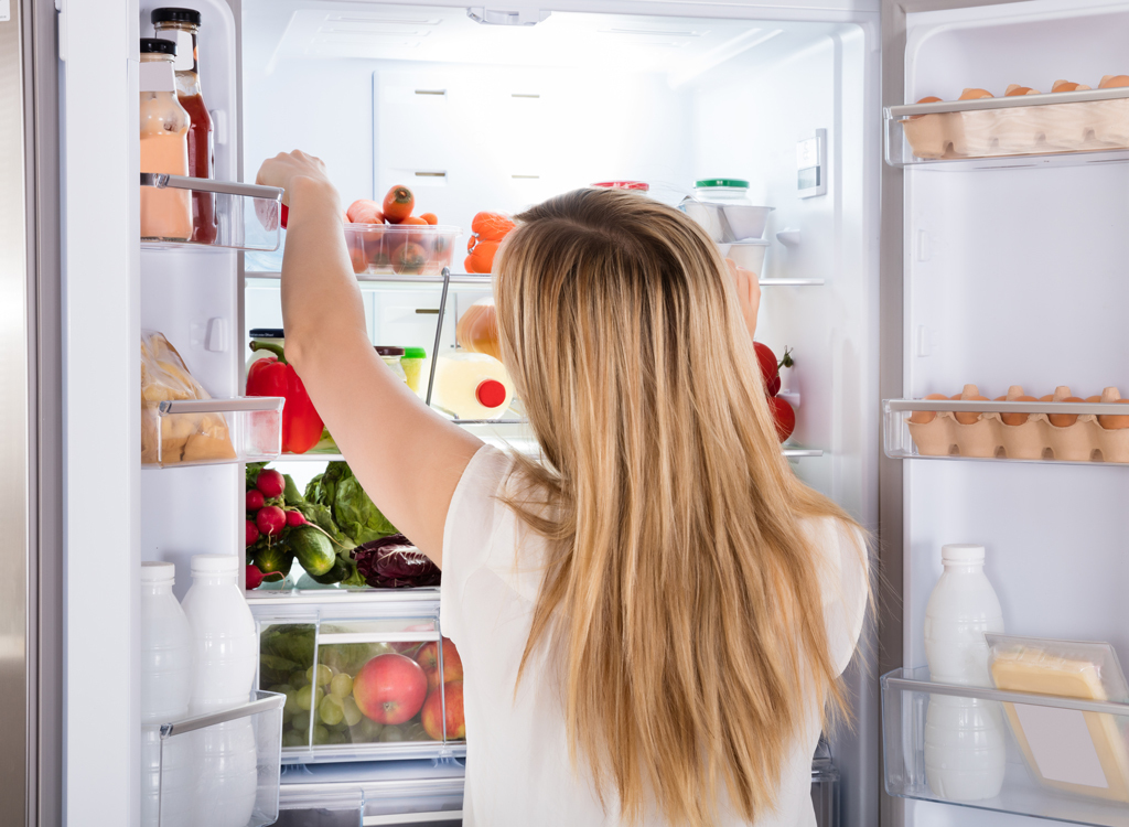 Hungry woman looking for food in fridge