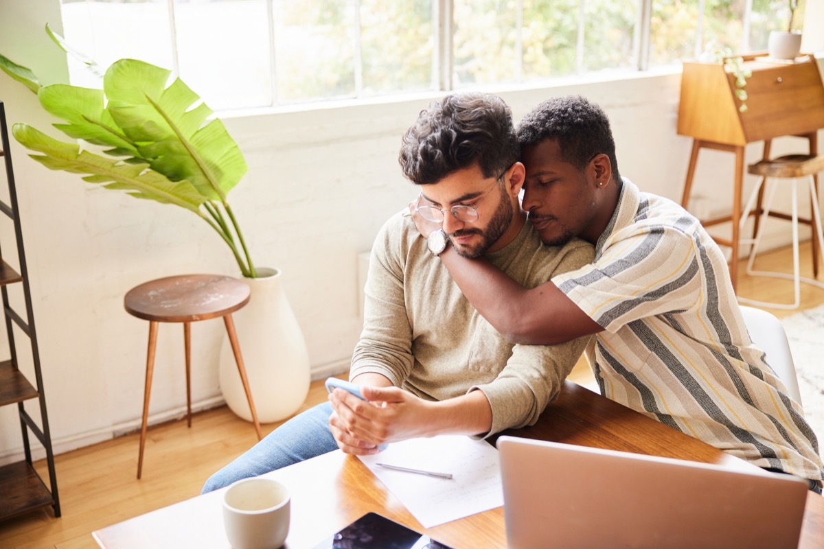 couple going over their their home finances on a laptop and smart phone while sitting at a table at home