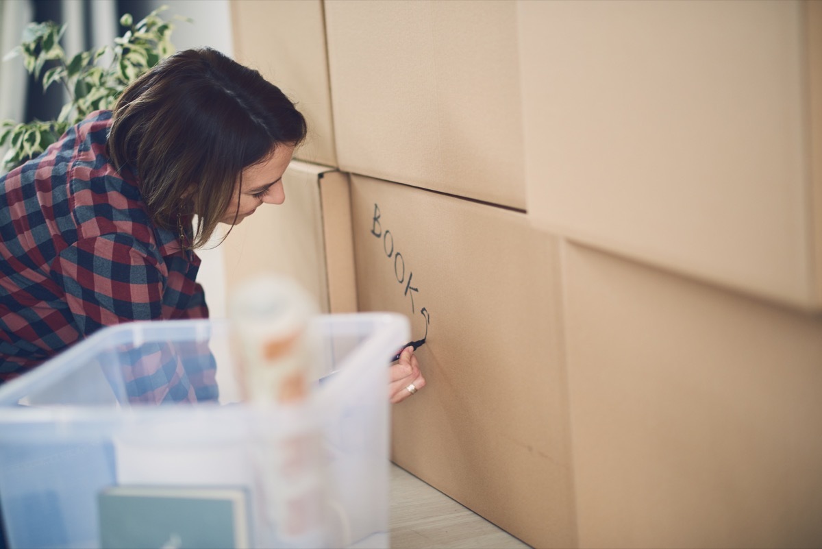 white woman writing on cardboard boxes