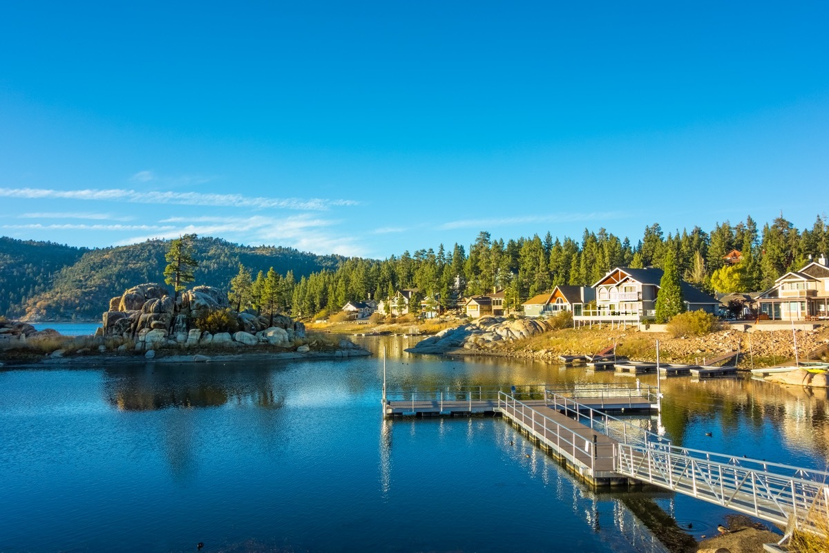 Reflections in the waters of Big Bear Lake at Boulder Bay fill the foreground leading back to vacations houses and the mountain ridges beyond, Southern California