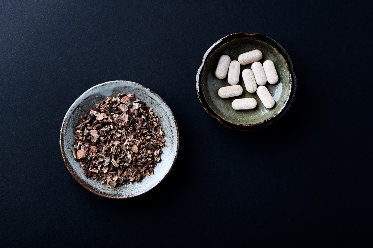 Dry root of Rhodiola rosea and tablets. Golden root, rose root. Dark paper background. Top view. Close up. Copy space.