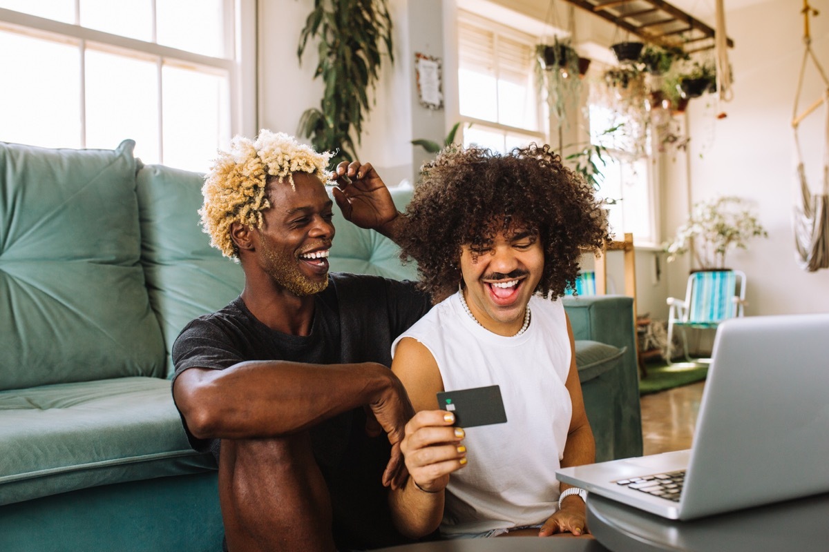 Cheerful young couple smiling cheerfully while shopping online at home.