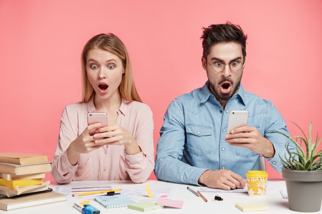 man woman looking at phones offended shocked