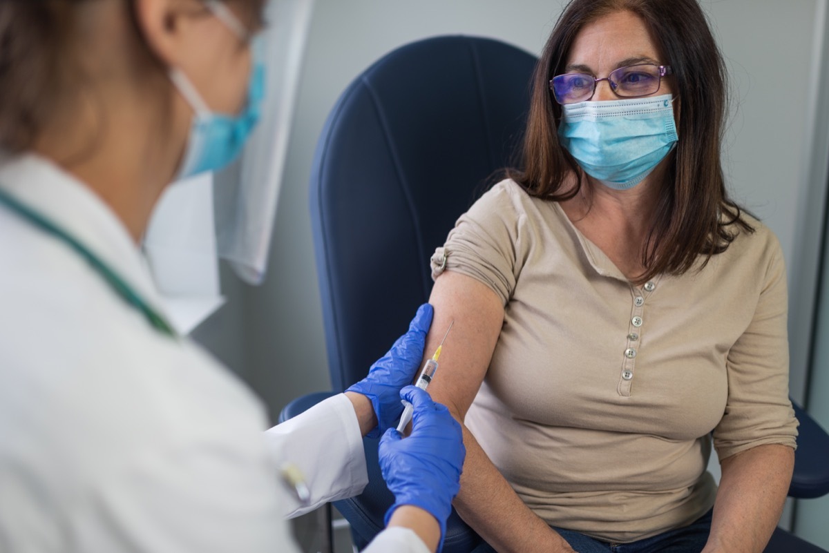 Close up of a mature woman taking a vaccine in her doctors office.