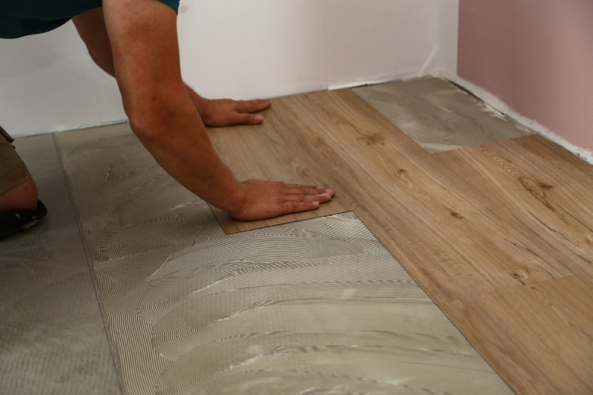 man installing wood grain tile floor