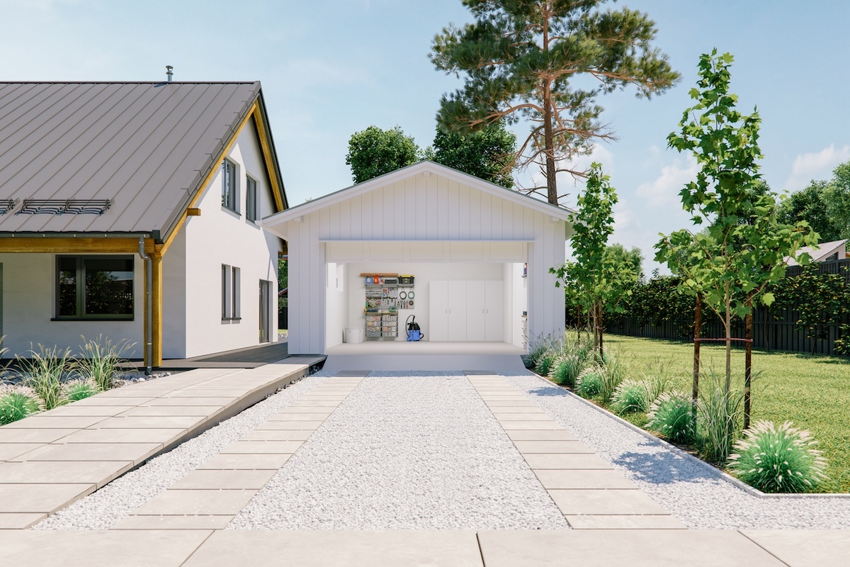 Open door of a modern, white garage with a white concrete and white stone driveway