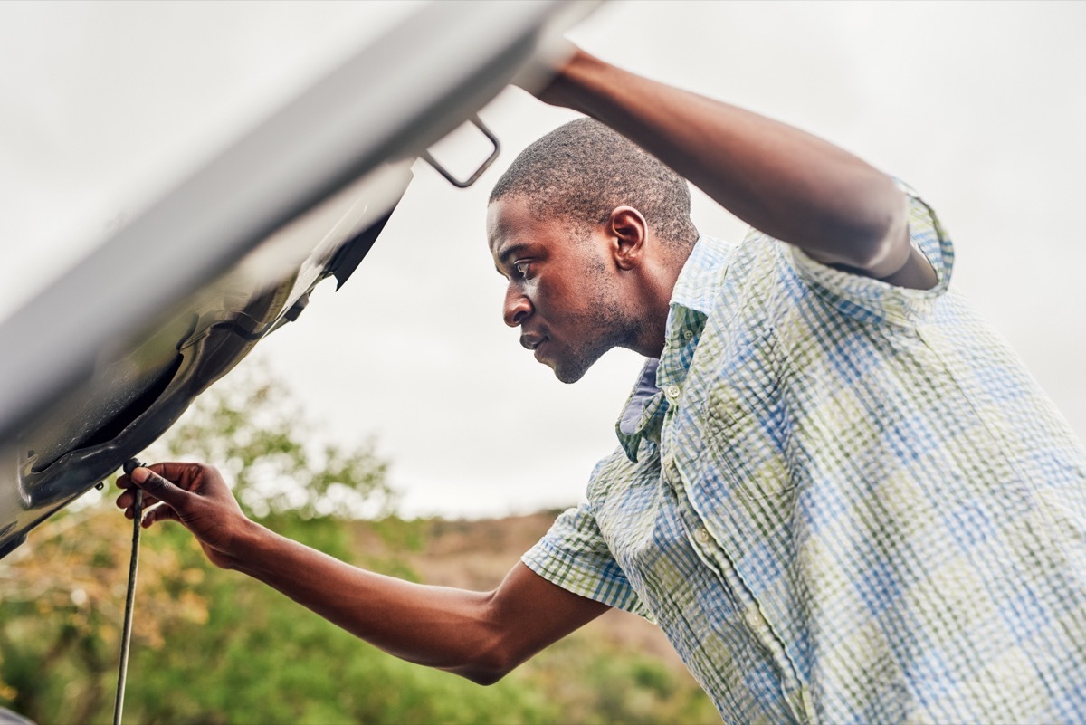 Cropped shot of a handsome young man looking under the hood of his broken down car outdoors