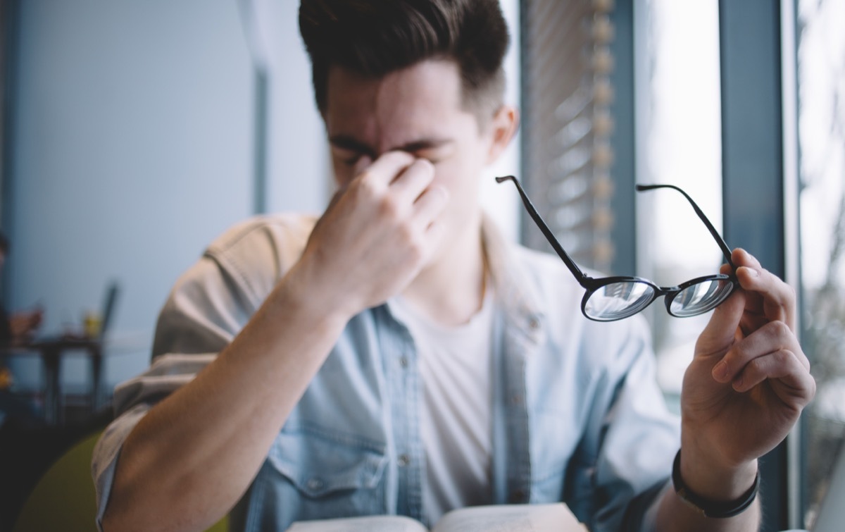 Man with glasses rubbing eyes