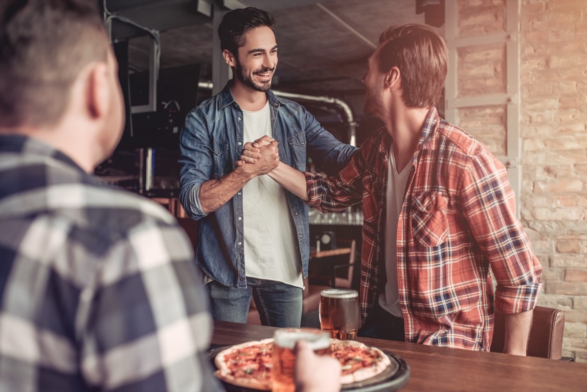 two young men shaking hands in a bar