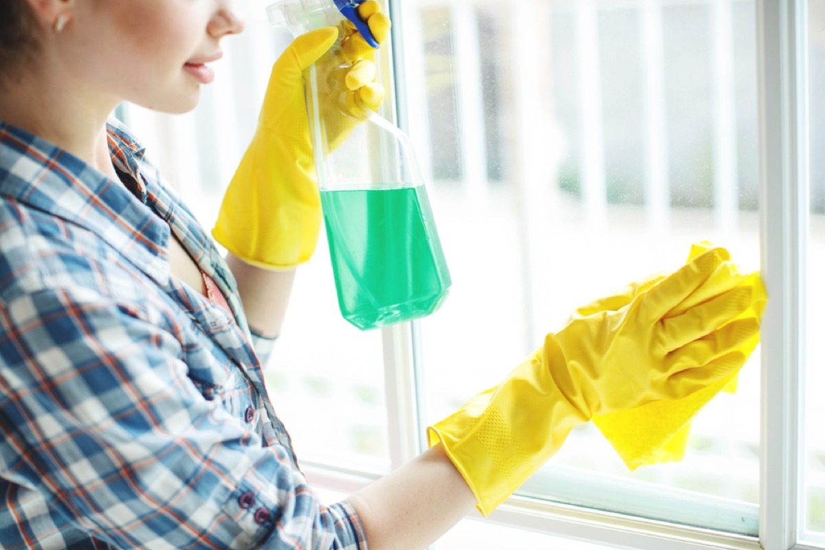 woman wiping window with cleaner, cleaning mistakes