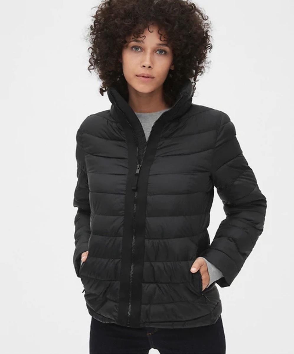 woman with curly hair wearing short black quilted jacket