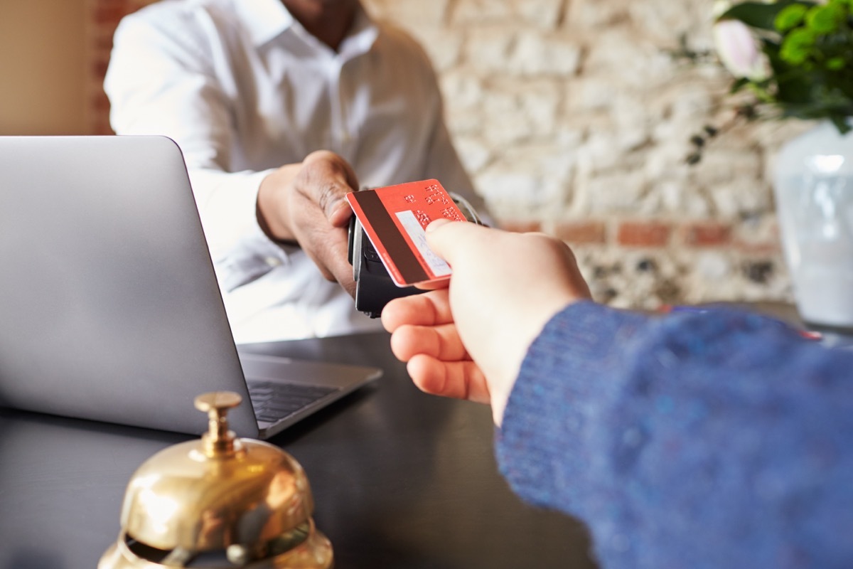 Guest makes card payment at check-in desk of hotel, detail