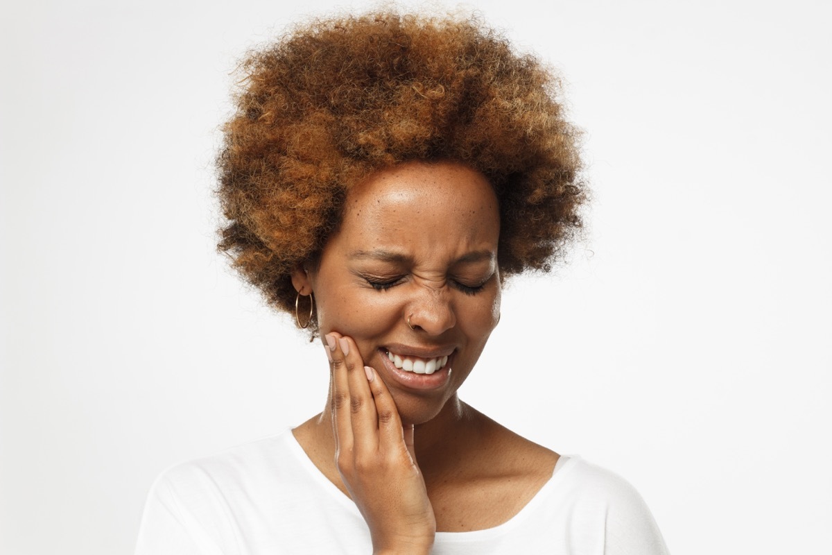 touching her face with expression of horrible suffer from health problem and aching tooth