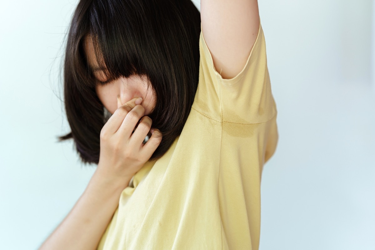 The woman in the yellow shirt covered her nose with her hands because she was sweating in her armpits and had a bad smell. Health care concept.