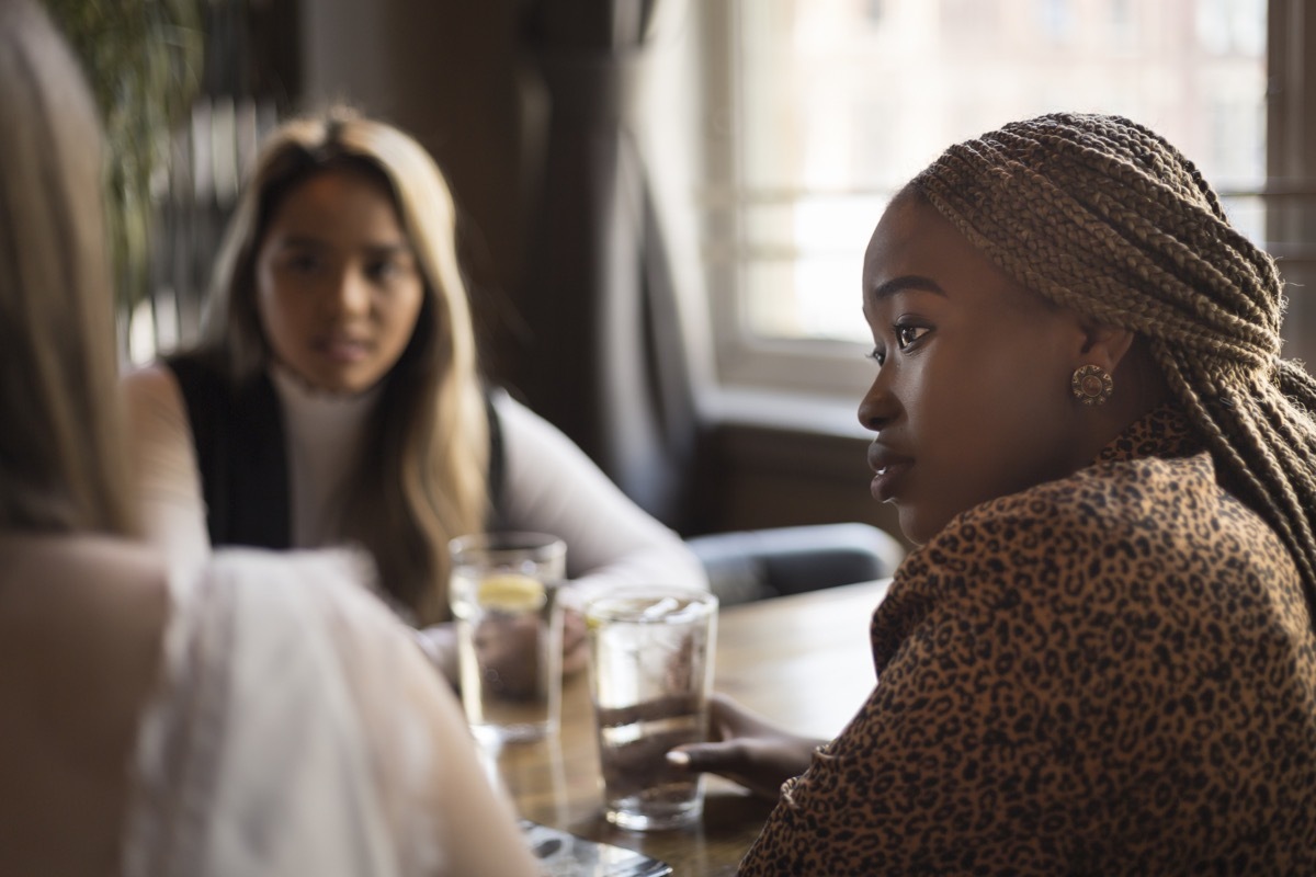 Young woman listening to her friends in a cafe bar