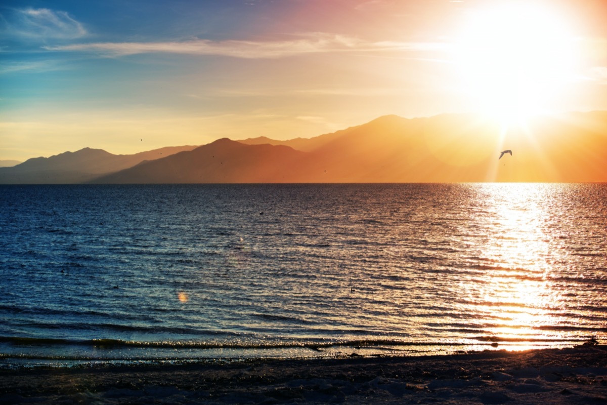 sunlight reflects off water with mountains behind it