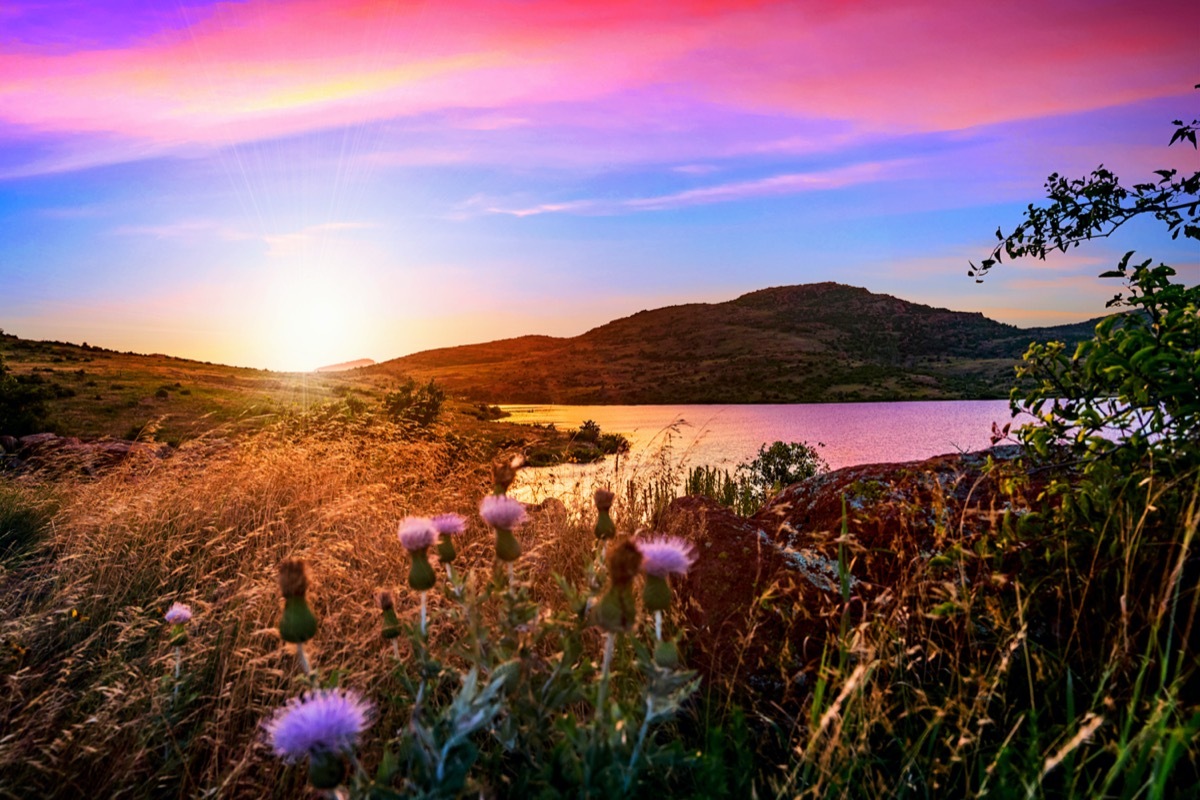 greens plants and a lake below the Wichita Mountains in Lawton, Oklahoma at sunset