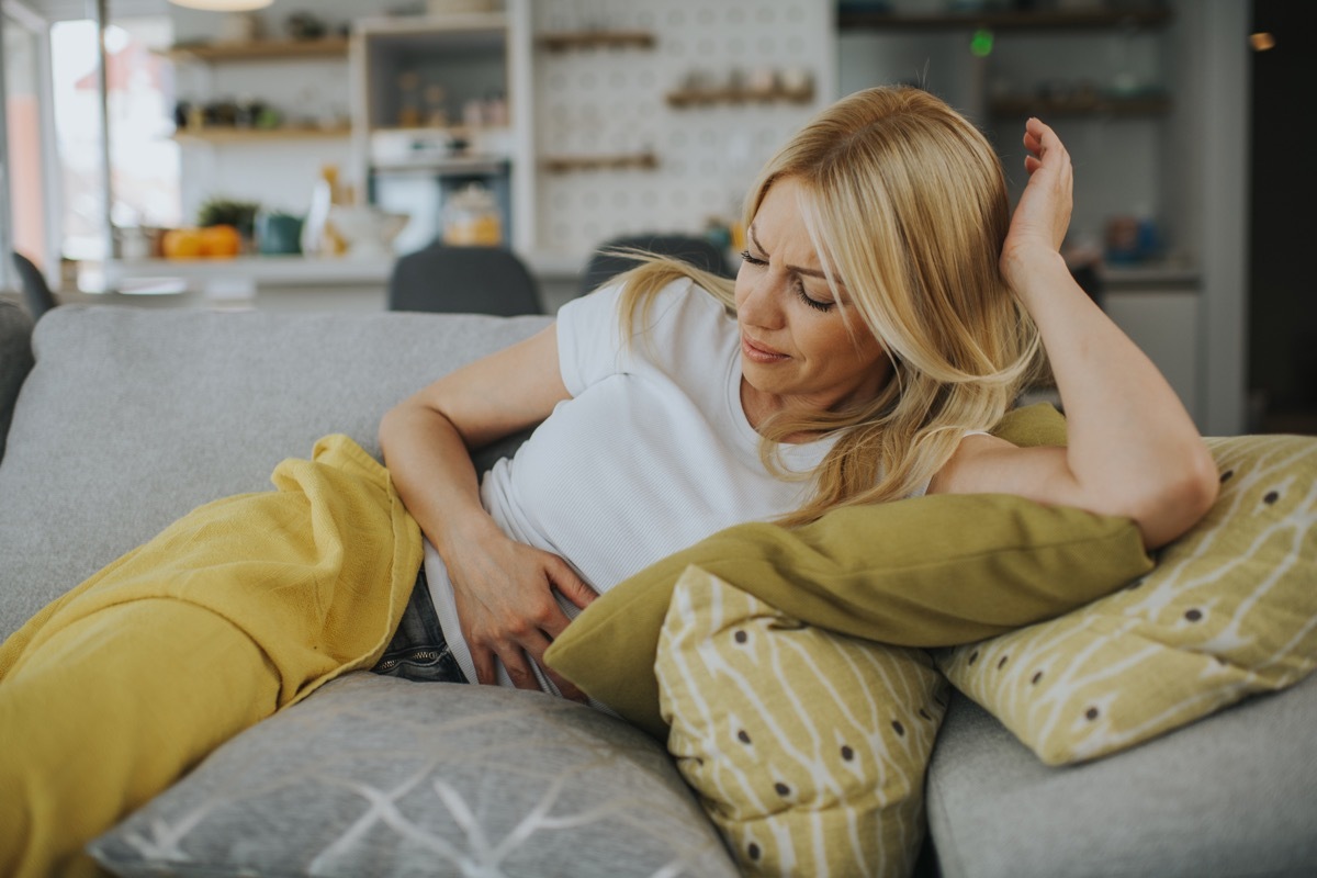 woman on couch with stomach pain