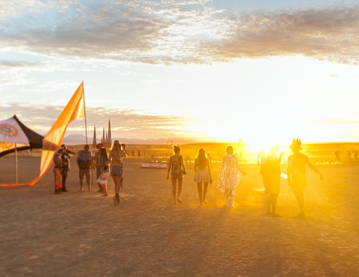 People walking towards sunset at a festival in the desert