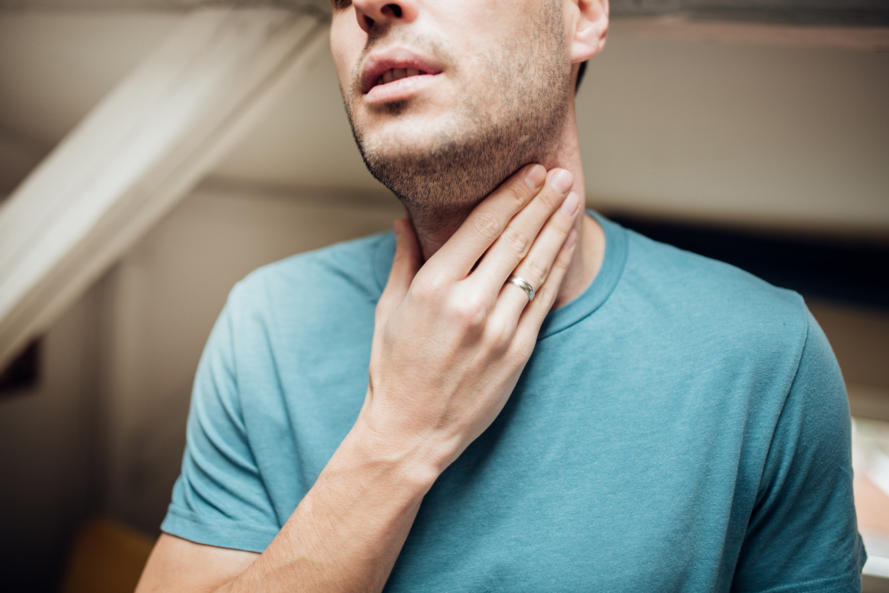 Man with hand on his neck and throat.