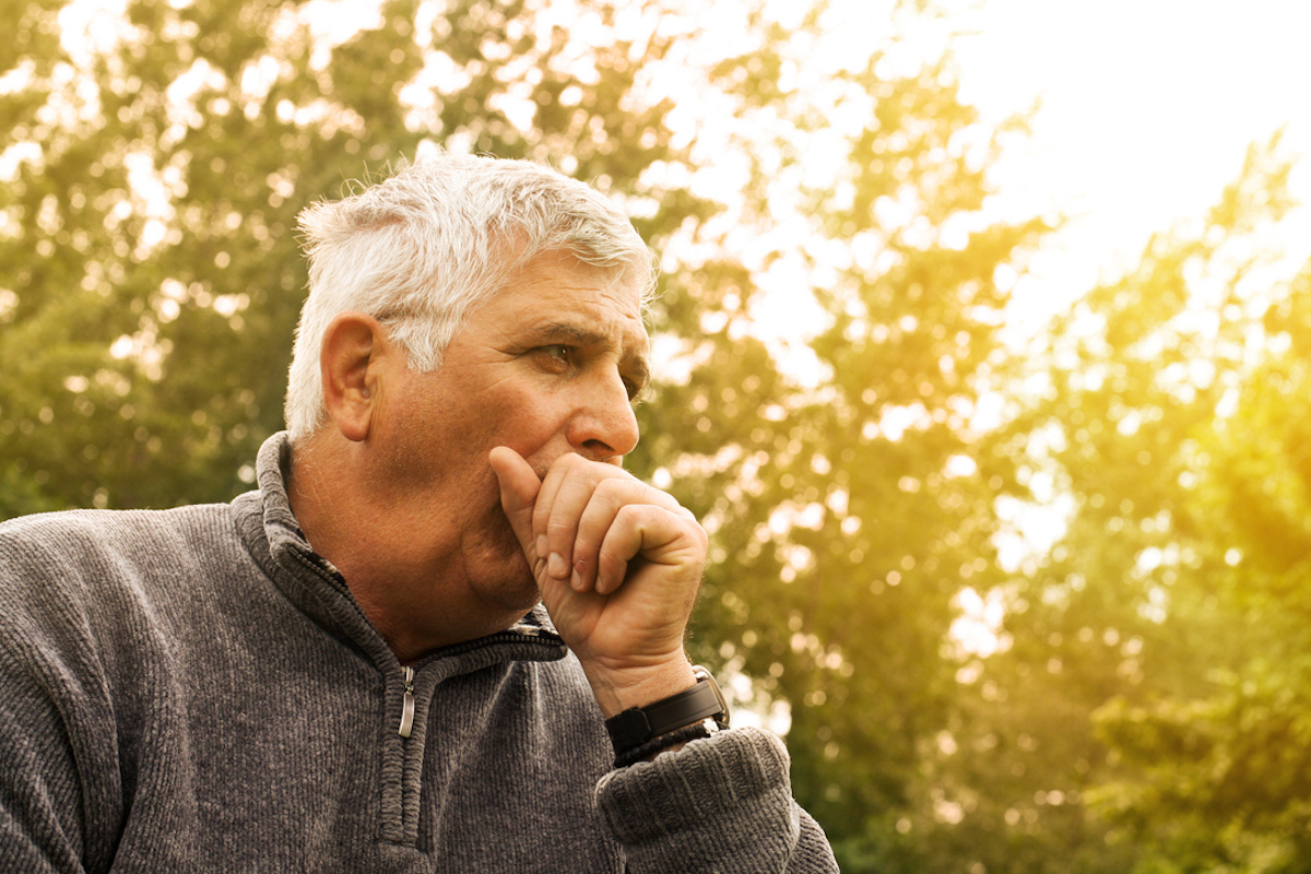 Coughing Senior Man on fresh air, considering symptoms of coronavirus