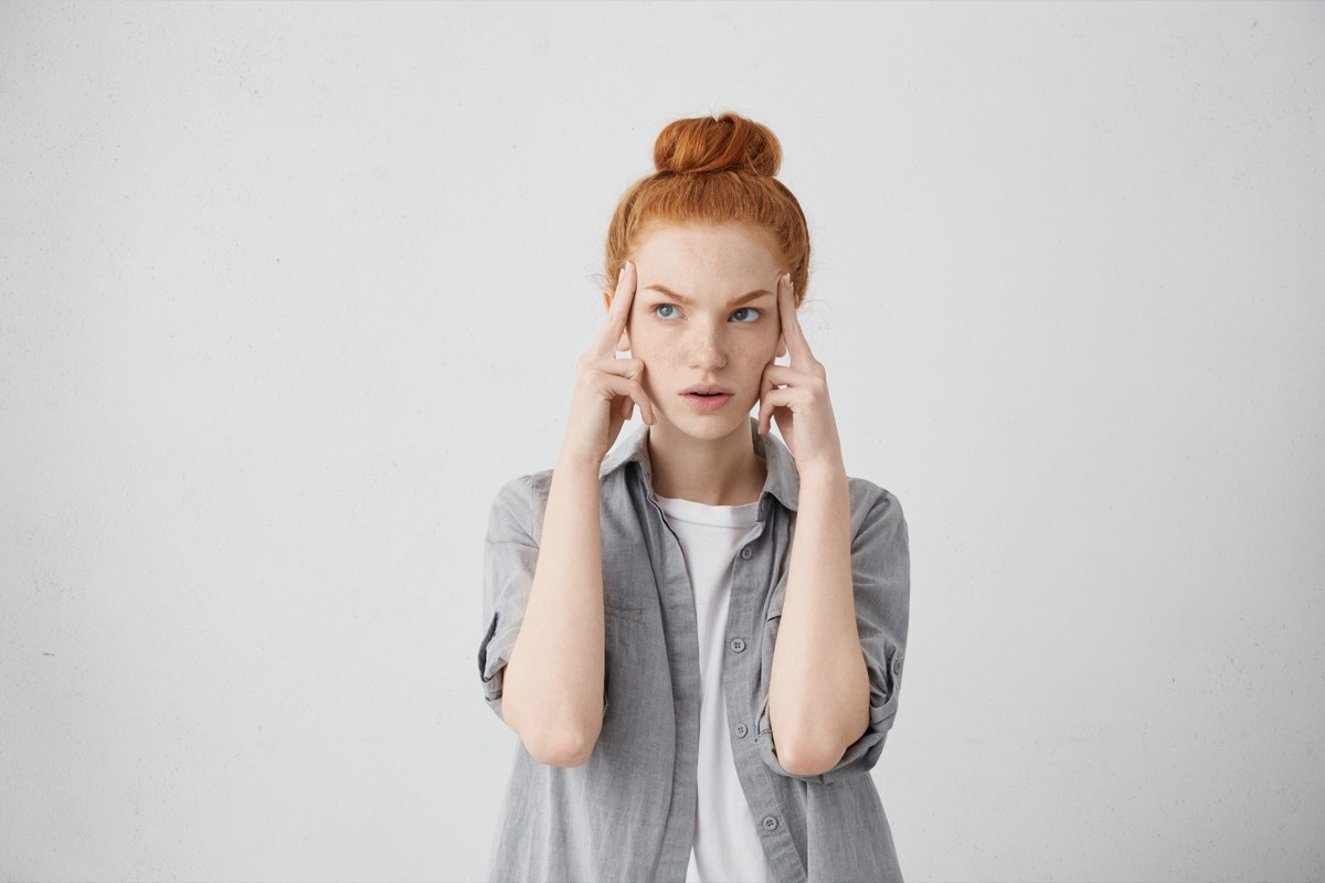 woman concentrating and holding her temples as she attempts to complete a series of logic puzzles