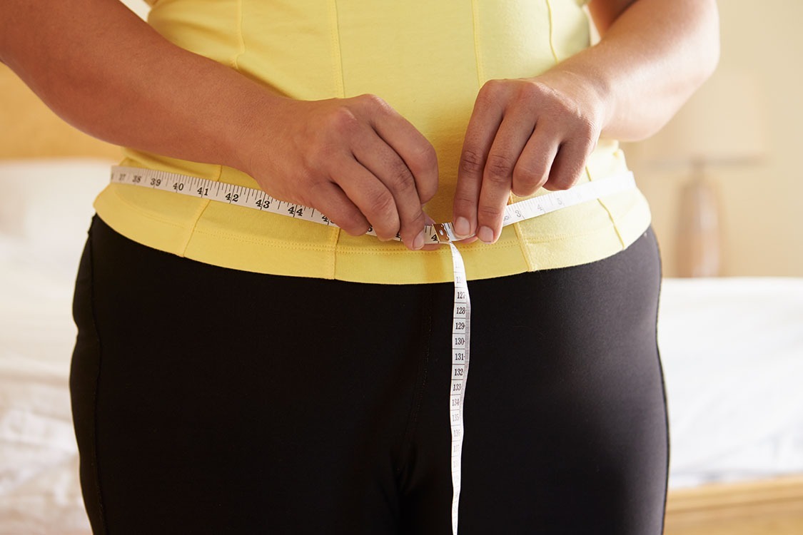 Woman measuring waist with measuring tape