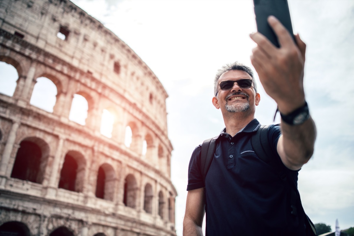 middle aged white man taking a selfie in front of the colosseum