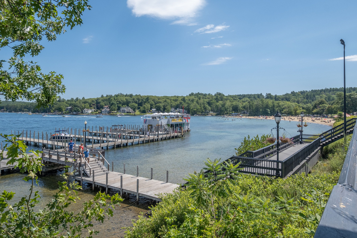 An aerial view of beach surrounded by water and growing trees with bridge in New Hampshire