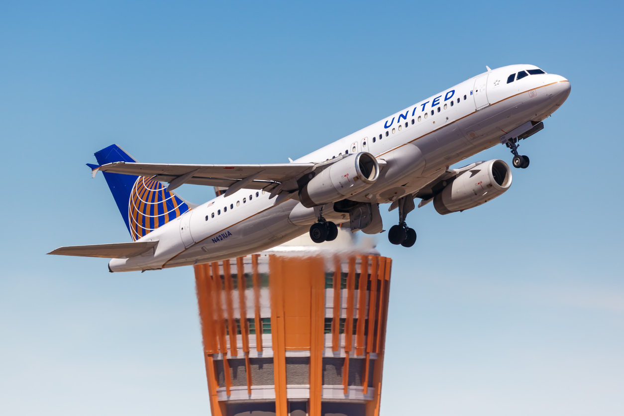 A United Airlines flight taking off from the airport with an air traffic control tower in the background