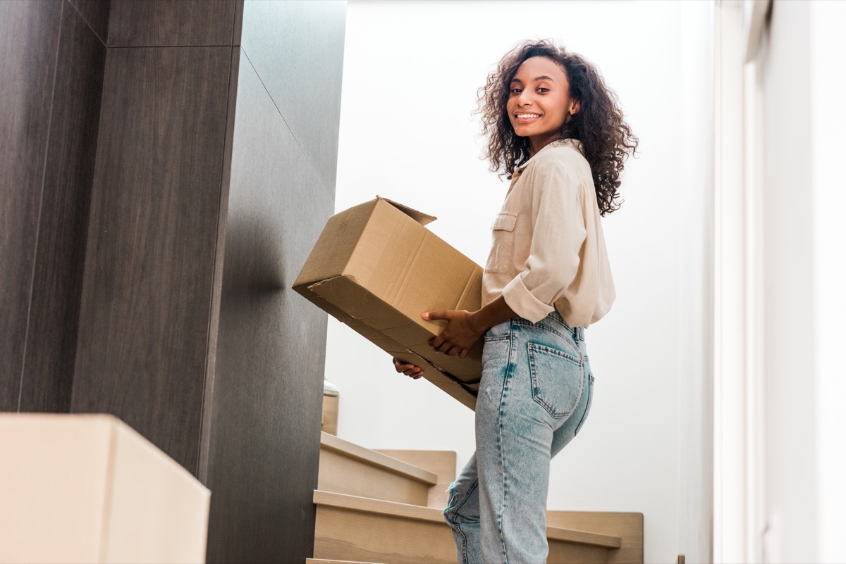 young black woman moving cardboard box upstairs