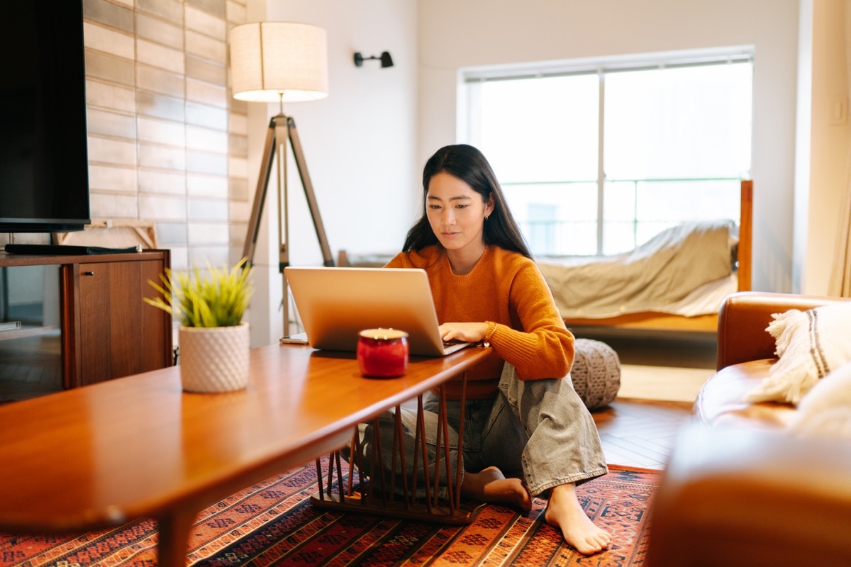 young asian woman using her laptop at the table at home