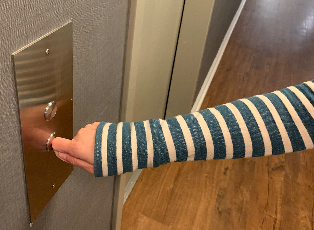 woman's hand pushing elevator button