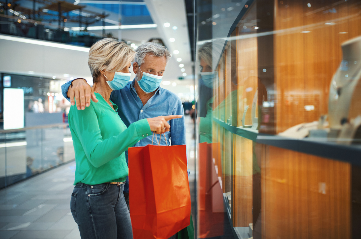 A middle-aged couple wearing masks shops for jewelry in a mall