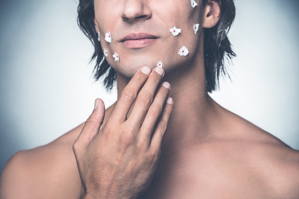 man with tissue paper over cuts on his face