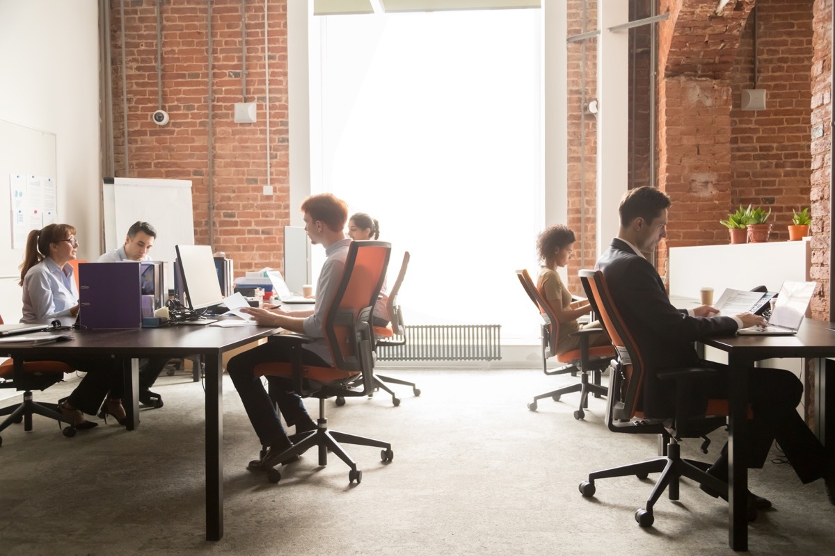 Business team women men workers working on computers in modern big coworking enterprise space, busy staff diverse professional employees office people group sitting at desks using pc at workplace