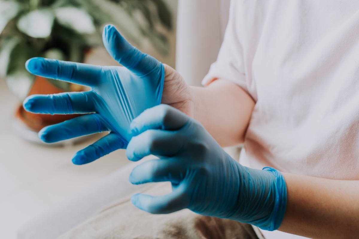 person wearing her latex surgical gloves at home before the cleaning process